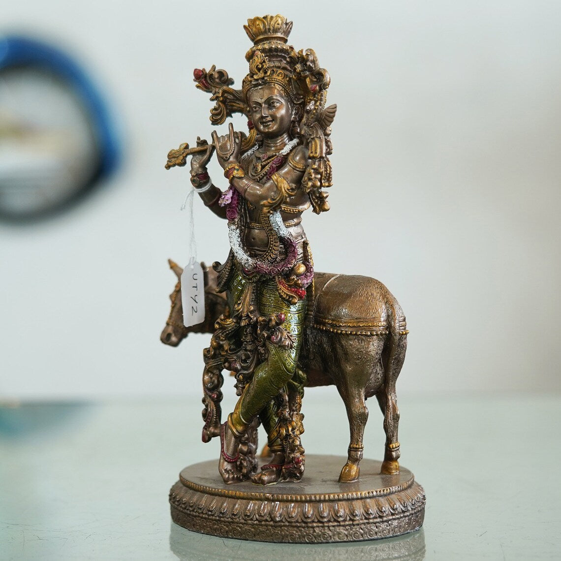 Handcrafted Polyresin Bronze Finish Lord Krishna Idol beautifully displayed on a shelf.